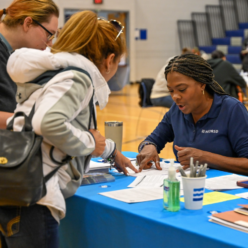 a customer service rep helps two customers at an outreach event.